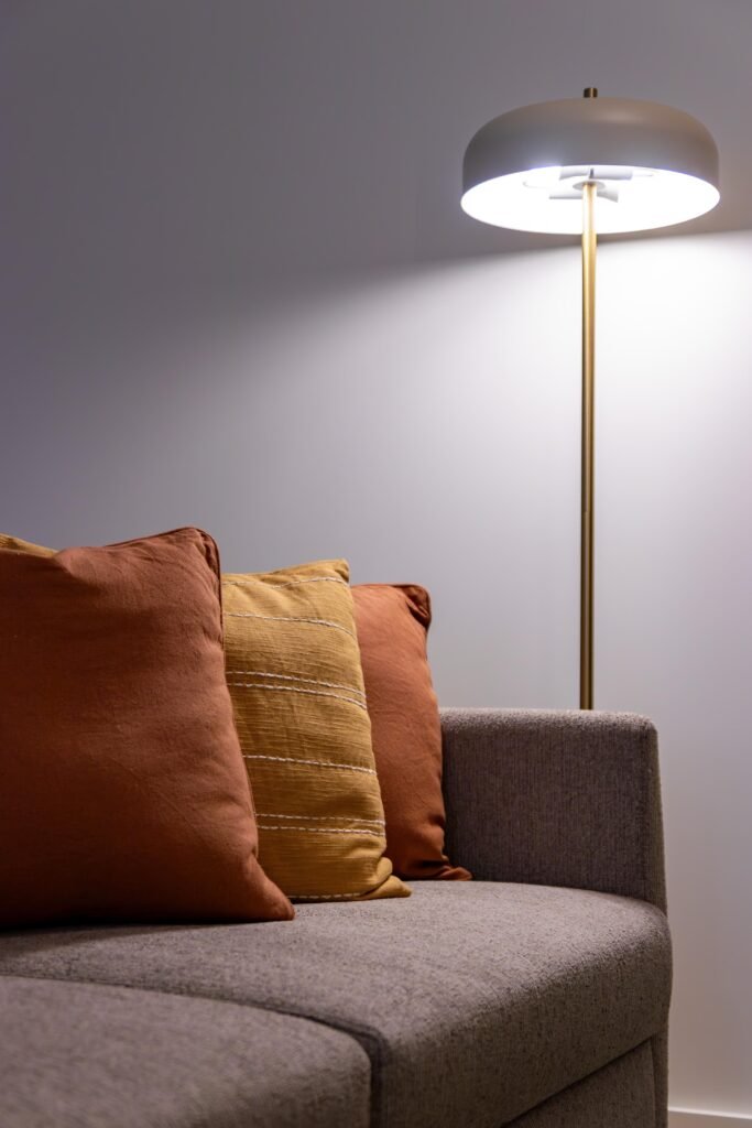 Cozy apartment sofa with warm floor lamp and fall-colored pillows