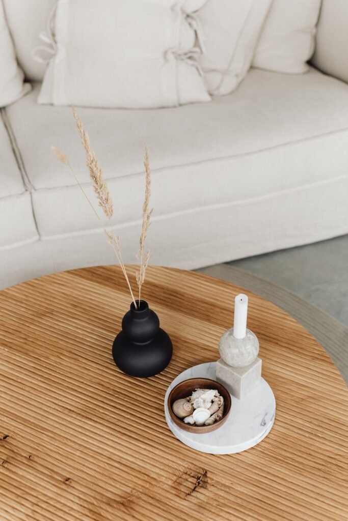 Minimalist apartment living room with a styled coffee table, decorative vase, candle, and neutral furnishings